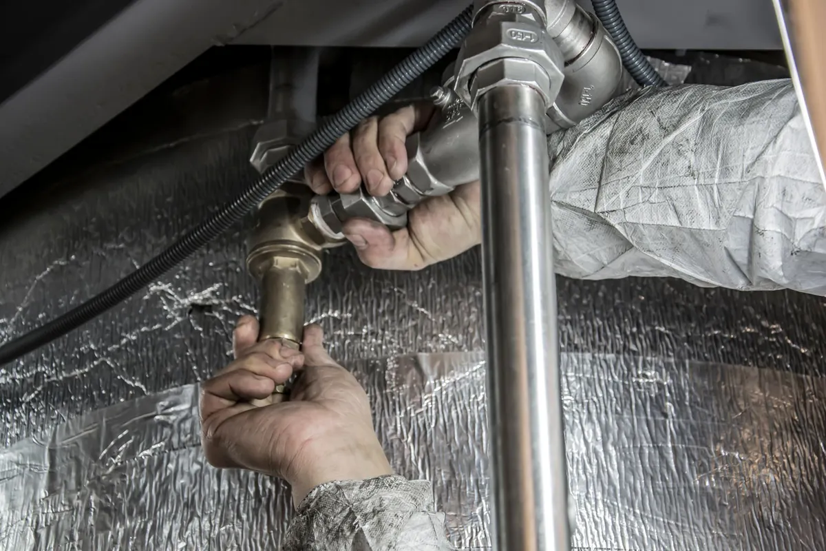 Hands at work on steel pipework during a repair