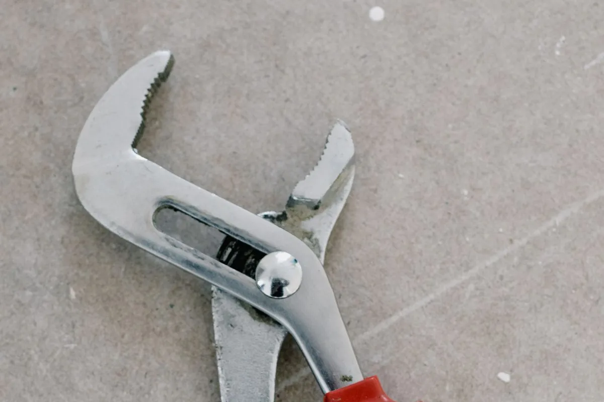 Pliers resting on a bare floor during a repair